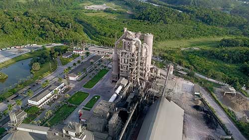 De acordo com a pesquisa de Informações Básicas Municipais (MUNIC) 2023 – Suplemento de Saneamento, divulgada pelo Instituto Brasileiro de Geografia e Estatística (IBGE) no final de novembro, 31,9% dos municípios brasileiros ainda utilizam os lixões para o descarte de resíduos sólidos no Brasil. Dentre esses resíduos estão os pneus, que podem demorar cerca de 600 anos para a sua decomposição, causando diversos danos, como a contaminação do solo e de lençóis freáticos e o acúmulo de água em seu interior, aumentando o risco de doenças, entre elas, a dengue. A boa notícia é que dá para evitar todos esses problemas com técnicas como o coprocessamento. Utilizada pela InterCement Brasil, uma das principais produtoras de cimento do país, essa tecnologia permite a substituição de combustíveis fósseis tradicionais (carvão mineral e coque de petróleo) por resíduos industriais e urbanos, biomassa e pneus inservíveis e não recicláveis, para a geração de energia térmica e como matéria-prima para a fabricação do cimento. “O coprocessamento é a melhor alternativa de destruição definitiva de pneus inservíveis. Um único forno, com capacidade de produção diária de mil toneladas de clínquer (mistura de calcário e argila, que é a base do cimento), pode consumir até cinco mil pneus por dia, o que significa a redução das emissões de gases, entre eles do efeito estufa, em 35%”, ressalta Cristiano Ferreira, Gerente de Coprocessamento da companhia. Somam-se a esses benefícios a diminuição de gastos e as ações de impacto social (renda para os participantes da cadeia de reciclagem), ambiental e de saúde pública, que se refletem em menos descartes em ruas, rios e em lixões, evitando a contaminação do meio ambiente e o aumento de criadouros de vetores de doenças transmitidas por roedores e mosquitos, por exemplo. Após serem recolhidos por usinas de beneficiamento, os pneus são triturados, separados dos metais e transformados em chips. Quando chegam à fábrica de cimento, são estocados e, em seguida, vão para a torre de aquecimento e para o forno. “A ideia da utilização de pneus no coprocessamento é reduzir a pegada de carbono, o impacto ambiental dentro da cadeia como um todo. Os combustíveis alternativos são menos poluentes do que os tradicionais e, ainda, permitem uma circularidade na coleta e no aproveitamento de resíduos”, fala Cristiano Ferreira. Ele explica que o processo de combustão não gera cinzas e resíduos poluentes. “Tudo acontece em um ambiente controlado. É uma operação combinada, que envolve a produção do clínquer, base do cimento, sem a geração de impactos ao meio ambiente”. A InterCement Brasil tem 10 fábricas em operação no país, que produzem mais de 8 milhões de toneladas de cimento por ano. Nesse processo, são reaproveitadas cerca de 90 mil toneladas de pneus, que evitam a emissão de 80 mil ton de CO2. “Hoje, 30% do nosso combustível no país vem de resíduos alternativos. Continuaremos investindo continuamente, olhando para o futuro e alinhados com as metas que o nosso setor vem estabelecendo. Ou seja, na promoção e intensificação do uso de fontes renováveis de energia, na redução das emissões de micropoluentes por tonelada de clínquer, na economia circular e na substituição de combustíveis fósseis por alternativos, incluindo biomassas e resíduos, entre outros itens”, pontua o executivo. O coprocessamento faz parte das metas de transição energética da companhia. De 2014 a 2023, a empresa investiu R$ 110 milhões, dos quais R$ 40 milhões em equipamentos e estruturas de coprocessamento e R$ 70 milhões na instalação e no comissionamento de filtro de manga na fábrica de Bodoquena (MS), em substituição ao filtro eletrostático existente desde 1993. “Nesse período, passamos de 17,5% de substituição térmica, registrados em 2014, para 28% em 2023, ou seja, um aumento de 60% de eficiência em cerca de dez anos. Isso significa que quase um terço dos nossos combustíveis vem de energias alternativas. O coprocessamento permite a redução de emissão de 300.000 toneladas de CO2 ao ano, quase mil toneladas por dia, em nossas operações”, finaliza o Gerente de Coprocessamento da Intercement Brasil, Cristiano Ferreira