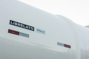 Librelato, uma das três maiores fabricantes de implementos rodoviários do Brasil, apresenta a nova Série Evolut 2026, um conjunto completo de implementos rodoviários que reúne avanços em leveza, robustez, eficiência estrutural e segurança. A marca apresenta ao mercado melhorias significativas em toda sua linha de produtos, reforçando seu compromisso com inovação e produtividade no transporte rodoviário de cargas. A pré-venda da Série Evolut 2026 tem início no dia 4 de dezembro, com condições comerciais atrativas. Com a Série Evolut 2026, a Librelato reafirma seu papel de vanguarda no mercado de implementos rodoviários. De acordo com João Librelato, Diretor Comercial e Marketing da Librelato, “a Série Evolut 2026 foi um projeto construído lado a lado com os clientes da marca, em que cada componente foi aprimorado para reduzir a tara e elevar o desempenho, mantendo intactas a qualidade e força que definem a Librelato. Com uma rápida resposta às solicitações dos clientes, conseguimos transformar suas necessidades em soluções práticas e inovadoras. É a nossa evolução mais robusta até o momento, estabelecendo novos padrões de qualidade, disponibilidade, segurança e rentabilidade por quilômetro rodado”. Em alguns modelos os ganhos foram expressivos, chegando até 630 quilos em termos de redução de tara, uso de materiais que garantem maior durabilidade aos implementos e a preocupação constante com a segurança no transporte. A Série Evolut 2026 aprimora a eficiência operacional e amplia a rentabilidade. Segundo João Librelato, “a nova Série Evolut 2026 estará disponível para pedidos em todas as concessionárias do País e para o mercado de exportação a partir do dia 4 de dezembro. A expectativa é de impactar os nossos clientes positivamente, uma vez que todas as inovações incorporadas à Série Evolut 2026 são resultado de uma forte aproximação das mais diversas realidades dos nossos clientes”, prevê. Rede Librelato se prepara com ação nacional de pré-vendas A partir de 4 de dezembro, toda a rede nacional e internacional de vendas da Librelato estará pronta para receber clientes interessados na aquisição da nova Série Evolut 2026. Os transportadores poderão procurar as concessionárias e representantes autorizados da marca para conhecer as condições comerciais exclusivas ainda para este ano e garantir a entrada em 2026 com a linha atualizada de implementos da Librelato. A Série Evolut 2026 contempla implementos destinados a diferentes segmentos, do agronegócio a operações portuárias e reforça a posição da empresa entre as três maiores fabricantes de implementos rodoviários do País, conforme divulgado em seus canais oficiais e portais institucionais. Projeto “Quem carrega o Brasil, carrega com Librelato” foi a base da Série Evolut 2026 A Série Evolut 2026 foi desenvolvida com base no projeto “Quem Carrega o Brasil, Carrega com Librelato”, que ampliou a escuta ativa desde o início deste ano. Ao longo do período, a empresa ouviu transportadores, geradores de carga, gestores de frota e motoristas de diferentes regiões do País, além de clientes internacionais, em um processo estruturado de ouvidoria que reuniu sugestões, relatos operacionais e demandas de melhoria. Os dados coletados foram analisados e rapidamente convertidos em ajustes técnicos e avanços de engenharia, resultando em uma resposta direta às necessidades identificadas pelos setores de engenharia de produto e marketing de produto. O trabalho deu origem à Série Evolut 2026, que chega ao mercado com aprimoramentos alinhados às expectativas dos transportadores e ao compromisso da Librelato com inovação, segurança e desempenho. Novos padrões de qualidade são estabelecidos com a nova Série Evolut 2026 “Não medimos esforços para revisitar toda a série e promover evolução em cada produto. Essa entrega reflete um dos valores da Librelato, que é ser comprometida com resultados — tanto aqueles que nossos clientes buscam na operação quanto os ganhos de excelência que alcançamos dentro do processo produtivo. Ao aprimorar projetos, processos e componentes, elevamos a performance em campo e, ao mesmo tempo, conquistamos mais agilidade e eficiência na manufatura”, afirma Rodrigo Corso, Diretor de Manufatura da Librelato. A partir desse marco, todo o portfólio Librelato passa a possuir as melhorias da Série Evolut 2026. Graneleiro Evolut 2026: mais leve, resistente e eficiente, reforçando a tradição da Librelato no transporte de grãos O modelo recebeu redução de até 200 quilos, resultado de ajustes no chassi e na caixa de carga. Principais melhorias: Perfil dianteiro redesenhado para evitar danos nos engates de freio. Tampas cerca de 5 quilos mais leves, facilitando o manuseio. Itens do chassi produzidos em aço de alta resistência, com redução de 80 quilos. Opção de estrutura em aço inox para aplicações severas. Soldagem robotizada e melhorias de vedação para evitar perdas de grãos. Basculante Evolut 2026: mais estabilidade e até 300 quilos a menos de tara Um dos modelos com maior ganho estrutural, alcançando redução de até 300 quilos na versão rodotrem. Destaques: Solda contínua na caixa de carga, eliminando pontos sem solda e reduzindo riscos de corrosão. Costelas dianteira, laterais e traseira com nova geometria, mais resistentes sem aumentar a tara. Borracha de vedação traseira com perfil em inox e sem rebites. Sistema de amortecimento com área de contato ampliada e fixação direta no chassi. Sinaleira traseira reposicionada para maior proteção. Nova geometria do dolly, permitindo manobras de até 90° e redução de 80 quilos. No semirreboque: novo cilindro, com menor tempo de basculamento. No bitrem: caixa dianteira redesenhada para melhor escoamento da carga Opção de revestimento interno em inox para ambientes corrosivos. Furgão Alumínio Evolut 2026: mais vedação e redução de peso Projetado para transportar cargas sensíveis e proteger contra chuva, poeira e demais intempéries, o Furgão Alumínio Evolut 2026 chega ao mercado entregando mais segurança para o transportador e redução de custos por quilômetro rodado. Estrutura de vedação reforçada, com fita especial nas emendas e mais pontos de fixação → vedação total. Testes de estanqueidade: luz, infiltração e inspeção visual. Teto com nova geometria e perfis em ômega, aumentando resistência estrutural. Assoalho reprojetado com perfis ômega, reduzindo cerca de 90 quilos. Porta 50 quilos mais leve e quadro reforçado, garantindo alinhamento e facilidade de abertura. Maior estruturação do quadro traseiro. Furgão Lonado Evolut 2026: redução de mais de 240 quilos na tara total Voltado para operações que exigem rapidez na carga e descarga, como transporte paletizado, bebidas e mercadorias diversas, este modelo chega com uma série de melhorias estruturais que aumentam a resistência, aprimoram a vedação e tornam a operação mais prática. A nova linha entrega ainda redução de mais de 240 quilos na tara total, contribuindo diretamente para maior capacidade de carga e melhor eficiência por quilômetro rodado. Melhorias principais: Testes de vedação iguais aos do Furgão Alumínio. Manutenção do padrão Evolut no assoalho e na porta traseira. Perfil superior com nova geometria para melhor fixação da borracha e menor entrada de água. Lona com proteção UV. Redução de colunas móveis em algumas versões (de 4 → 3), diminuindo peso em até 100 quilos. Roldana da coluna reprojetada, facilitando abertura e fechamento da lona. Porta Contêiner Evolut 2026: redução de tara em até 630 quilos na versão de 12 pinos A versão Porta-Contêiner da Série Evolut 2026 foi redesenhada para atender às demandas crescentes da logística portuária e do transporte marítimo. Os barrotes foram redimensionados e passaram a ser soldados por processo robotizado, garantindo maior precisão. Essa solução, aliada a redimensionamentos na estrutura do chassi, permitiu reduzir o peso em até 630 quilos na versão de 12 pinos e 260 quilos na versão de 4 pinos, ampliando a capacidade de carga útil sem comprometer a resistência. Principais evoluções: Barrotes redimensionados e soldados por processo robotizado. Optimizacão do sistema luminoso, eliminando suportes e reposicionando LEDs para evitar danos. Suporte de sinaleiras parafusado, permitindo reposicionamento conforme operação. Maior ângulo de entrada, facilitando acoplamento e reduzindo riscos de danos. Batentes adicionais para proteção traseira em terminais. Tanque Evolut 2026: mais segurança no transporte de líquidos perigosos A nova linha Tanque ficou cerca de 260 quilos mais leve, nas versões de semirreboque, e 500 quilos, nas versões de bitrenzão. Tudo isso devido as revisões estruturais que reduzem a tara sem comprometer a robustez, ampliando a capacidade de carga útil e garantindo operações mais econômicas e seguras. Destaques: Nova geometria das bocas de carregamento, mais seguras em caso de tombamento. Eliminação da plataforma superior, reduzindo cerca de 180 quilos. Corrimão com geometria simplificada e mais seguro para acesso. Recuperadora de vapor reposicionada internamente, mais protegida e 80 quilos mais leve (botton loading). Suportes de extintor agora parafusados, facilitando substituição. Suporte de estepe reforçado para suportar vibrações severas. Atende NR-35 e regulamentações do Inmetro, com aferição realizada na fábrica. No press kit https://drive.google.com/drive/folders/1VCBewOmhP-E0upHk2nkjswalnbeFypX0?usp=sharing você encontra mais opções de fotos da Série Evolut 2026, das plantas da Librelato, dos Executivos, do processo produtivo e muito mais.